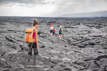 Fotobehang Hiking group of hikers walking on Hawaii volcano lava field hike adventure happy woman with backpack in Big Island, Hawaii. Tourists walking on guided tour trail outdoor USA summer travel vacation. © Maridav