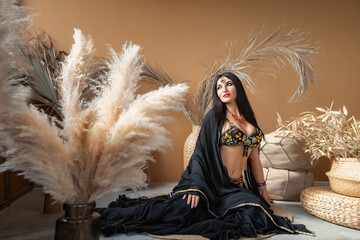 a beautiful brunette woman in a scheherazade belly dance costume lies in the eastern entourage