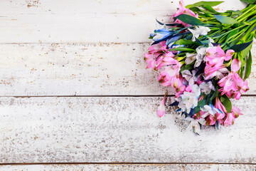 Beautiful bouquet of pink and blue alstroemerias on wooden background.