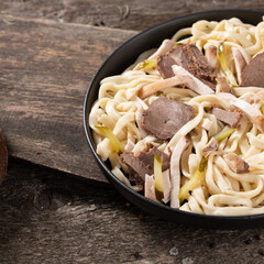 Food noodles with meat close-up on a plate on a wooden table. Delicious food concept.