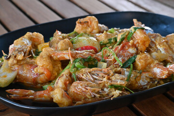 A Stir fried shrimp with curry powder on a vintage brown table in Thai restaurant.