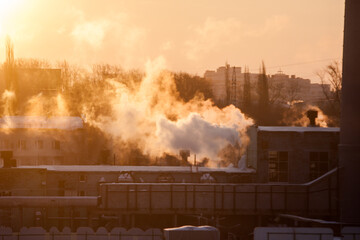 Obraz premium steam from the boiler room pipes in the contoured light of dawn, urban landscape