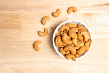 Top view roasted golden cashew nuts on white bowl healthy food protein-rich.