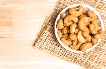 Obraz na płótnie Canvas Top view roasted golden cashew nuts on white bowl healthy food protein-rich.