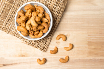 Top view roasted golden cashew nuts on white bowl healthy food protein-rich.