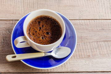 Black coffee in a white cup on a wooden background