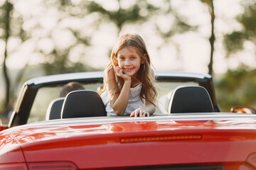 Family in a cabriolet convertible car at the sunset