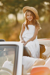 Family in a cabriolet convertible car at the sunset