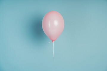 Pink balloon on a blue background. A balloon filled with helium flies on a copy space, on an empty wall.