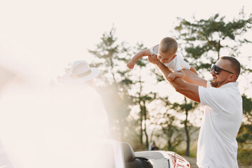 Family in a cabriolet convertible car at the sunset