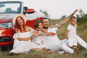 Family sitting by the red cabriolet
