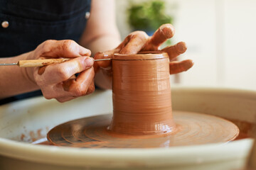 Women's hands work with raw clay on a potter's wheel. Master class on making a jug.