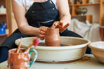 Female hands of a potter working on a circle. Traditional folk crafts.