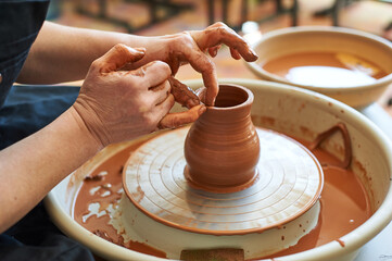 Female hands working on a potter's wheel making a jug.