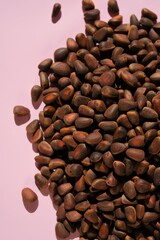 Pine nuts heap on a pink background. Nuts and seeds. 