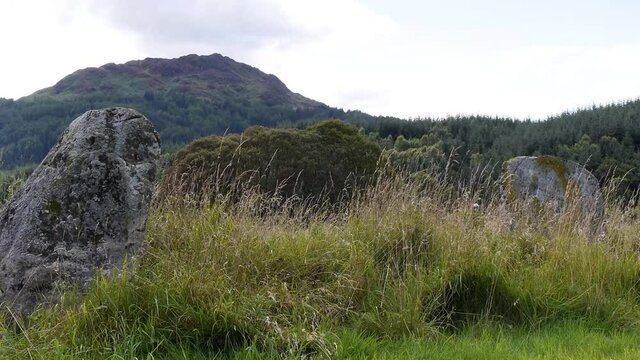 View of two standing stones at Kindrochet, with a mountain background. Filmed near Comrie, Scotland.