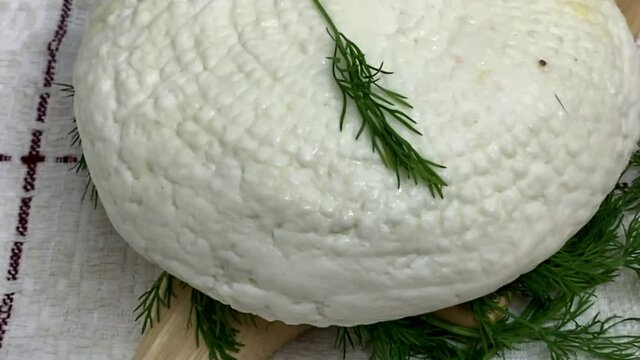 Round soft white homemade cheese. Adyghe cheese with greens lying on wooden board. HD