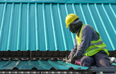 Obraz premium Roof constructionConstruction worker install new roof,Roofing tools,Electric drill used on new roofs with Metal Sheet.