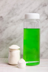 Heap of white protein powder with measuring spoon and bottle