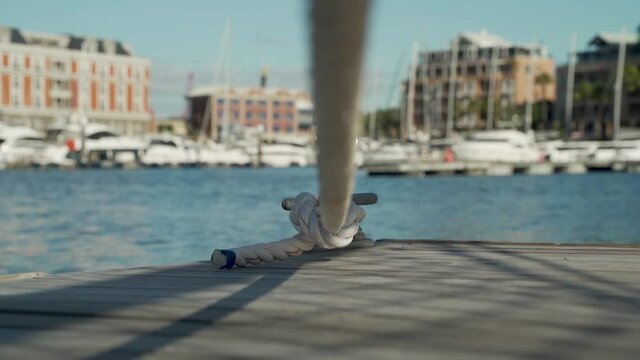 Tracking shot passing under a docking line at a harbour with boatings in the background