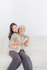 Obraz premium close up old woman, young Asian female hug old female in home, they feeling happy and smile, they sitting on sofa, mother's day, happiness elderly in family time