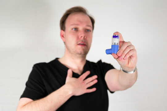 Man using a blue asthma spray inhaler