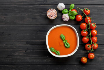 Tomato cream soup with garlic and basil on wooden table. Vegetarian recipe, healthy lunch. top view, copy space