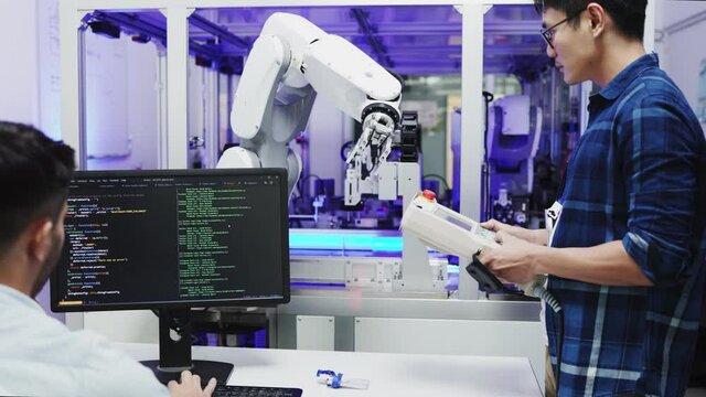 Asian Engineers Maintenance Robot Arm at Lab. they are in a High Tech Research Laboratory with Modern Equipment. Professional Japanese Development Engineer Testing an Artificial Intelligent.