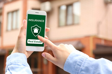 Woman with mobile phone applying for real estate online outdoors