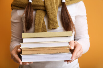 Woman with stack of books on color background, closeup