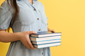 Woman with stack of books on color background