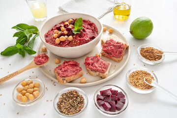 Close-up of a red beet hummus dish with surrounding ingredients