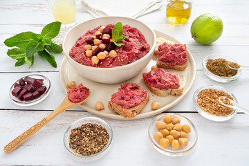 Close-up of a red beet hummus dish with surrounding ingredients