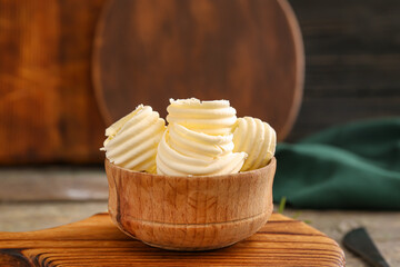 Bowl with fresh butter on wooden background