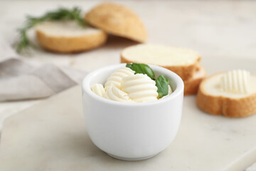 Bowl with fresh butter and basil on light background