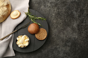 Bowl with fresh butter and bread on dark background