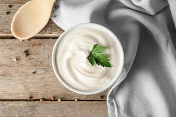 Bowl of tasty sour cream on wooden table
