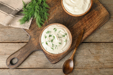 Bowls of tasty sour cream on wooden background