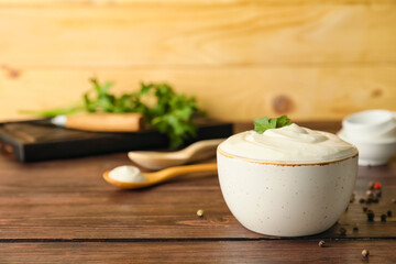 Fototapeta na wymiar Bowl of tasty sour cream on wooden background