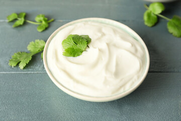 Obraz na płótnie Canvas Bowl of tasty sour cream and herbs on color wooden background