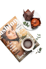 Cup of coffee with magazine on white background