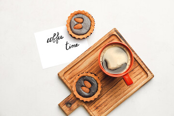 Board with cup of coffee and cakes on light background
