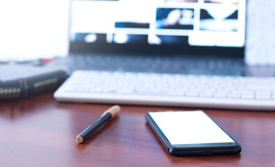 Phone and pen on the table. Blank white screen. Computer keyboard. Office workplace. laptop