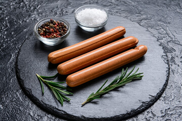 Slate plate with tasty sausages and spices on dark background