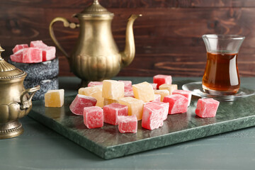 Composition with Turkish delight and cup of tea on table