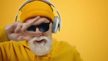 Joyful old man listening music in headphones indoors. Mature guy dancing inside. - Powered by Adobe