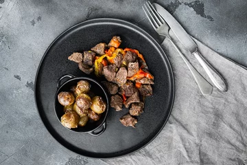 Deurstickers Beef meat stewed with potatoes, carrots and spices, on gray stone background, top view flat lay © Ilia Nesolenyi