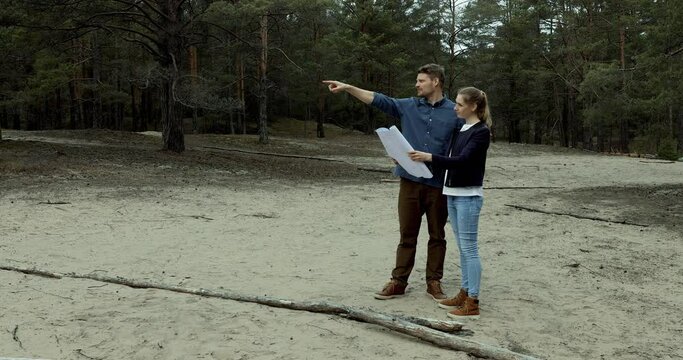 young couple choosing a plot of land for forest lodge construction