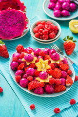 Fresh dragon fruit salad with strawberries, rspberries and start fruit (carambola)