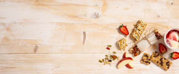 Homemade muesli bars with strawberries, yogurt and apple on wooden background